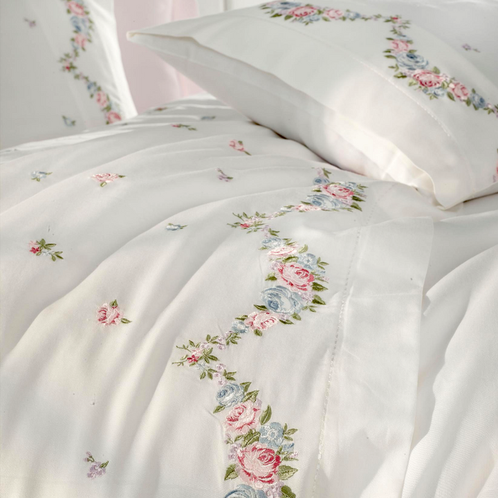 Pink, blue, green floral embroideries on white duvet cover makes a combination with pink bed sheet